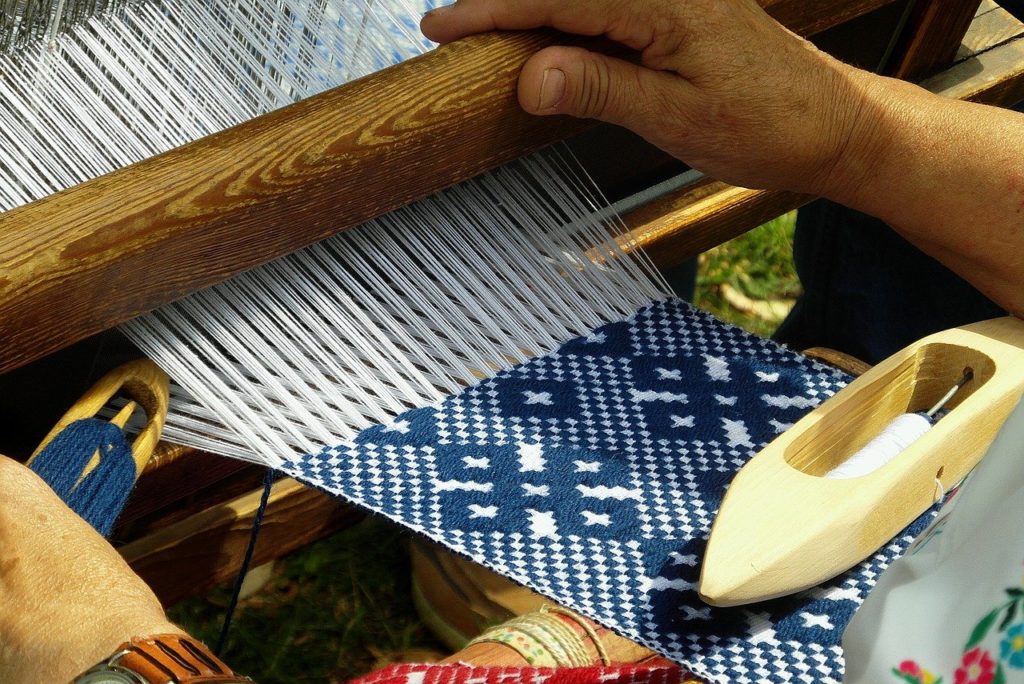 Image of a hand waving loom with a blue and white fabric being created