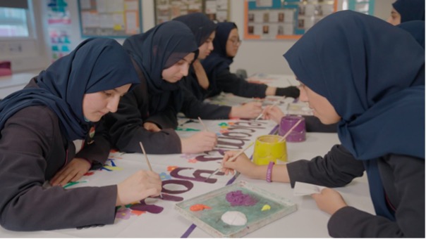 A group of female pupils painting on paper.
