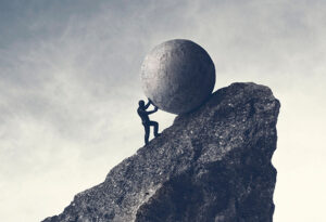 Black and white image of a person pushing a large boulder up a rock face