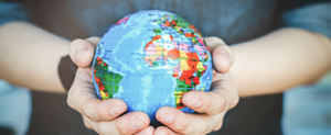 A globe held in two hands in front of a person